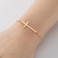 Primer plano de una pulsera minimalista de oro con colgante de cruz en la muñeca - Dorado