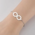Detalle de una pulsera plateada con símbolo de infinito en la muñeca con brillo - Color Acero