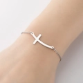 Detail van de zilveren roestvrijstalen kruisarmband met gebogen hanger om de pols - Zilver