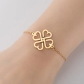 Bracciale a quadrifoglio con cuori dorati lucidi indossato sul polso per un look elegante - Oro