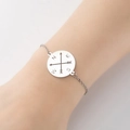 Close-up of silver stainless steel compass charm bracelet on woman's wrist - Steel