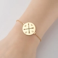 18K gold plated stainless steel compass pendant bracelet worn on a woman's wrist - Gold