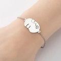 Vista detallada de pulsera minimalista plateada con colgante de cara abstracta calada - Color Acero