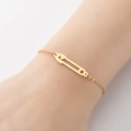 Bracciale minimalista in oro con ciondolo a spilla da balia su polso femminile moda - Oro