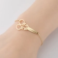 Brazalete dorado vintage con forma de tijeras y detalles grabados en cadena fina - Dorado