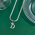 Silver crown letter D pendant necklace with flat snake chain on green textured background - Letter D
