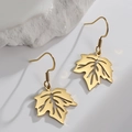 Pendientes de hoja de arce dorada con vetas huecas sobre fondo de piedra minimalista - Dorado