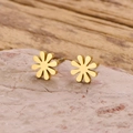 Macro view of gold daisy stud earrings on stone showing petal details and metal texture - Gold