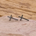 Detail of matte black stainless steel cross earrings on a natural stone base - Black