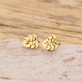 Detalle de los pendientes de hoja bañados en oro de 18K sobre superficie de piedra - Dorado