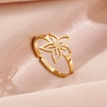 Polished gold flower ring with cutout petals on pink satin fabric background - Flower Gold