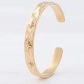 Nahaufnahme eines goldenen Armreifs mit Sternen-Gravur und gehämmerter Oberfläche - Stern Gravur Stil