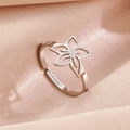 Minimalist silver stainless steel hollow flower ring on soft pink satin fabric - Flower Steel