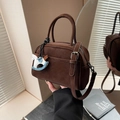 Sac bowling marron mat avec doubles poignées et breloque cheval sous une lumière chaude - Café Avec Pendentif