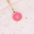 Dettaglio del pendente stella dorata con smalto rosa su sfondo di pietra rustica - Stella Rotonda Fucsia
