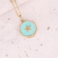 Dettaglio macro del ciondolo a stella dorata con smalto blu su superficie in pietra - Stella Rotonda Blu Lago