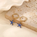 Detailed shot of gold starfish earrings with blue enamel finish on a stone surface - Blue Starfish Hoop Earrings (Pair)