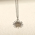 Vista macro dettagliata della collana con ciondolo a girasole argento e viso inciso - Girasole / Colore acciaio
