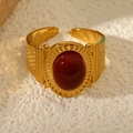 Dettaglio anello vintage dorato con pietra ovale rosso scuro e rilievi incisi - Rosso