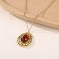 Gros plan du collier doré rétro avec pendentif pierre rouge foncé et texture martelée - Jaspe Rouge