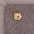 Nahaufnahme des goldenen Evil-Eye-Anhängers mit grünem Edelstein und Reliefdetails - Auge mit grünem Diamanten