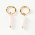 Detalle de pendientes de aro dorados con colgantes cilíndricos de piedra rosa claro - Blanco