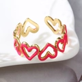 Detalle de anillo ajustable dorado con corazones de esmalte rosa en bandeja cerámica - Rojo