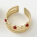 Macro shot of gold layered stainless steel ring with red gemstones and wavy texture - Gold with Red Stone