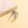 Unique silver stainless steel wing ring with layered cutout design on a warm textured base - Feather Wing Style / Steel