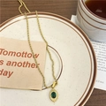 Collier chaîne torsadée dorée avec pendentif en malachite verte sur une assiette blanche - Acier Inoxydable/Acier Titane/Zircone / Ovale en Pierre Verte
