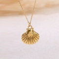 Detailopname van gouden schelphanger aan fijne schakelketting met gedetailleerde textuur - Sint-jakobsschelp