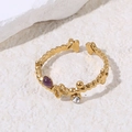 Primer plano de anillo dorado ajustable con gema púrpura, cristales y dijes de mariposa - Morado