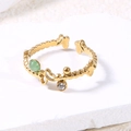 Detalle de anillo ajustable dorado con mariposas, perla verde y circón sobre base de piedra - Verde