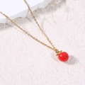 Detailed macro view of a red enamel apple pendant on a thin gold chain necklace - Apple