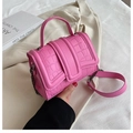 Rosafarbene Umhängetasche mit Krokostruktur und Metallkette auf weißem Stoff - Rosa