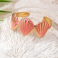 Close-up of golden shell bracelet with pink enamel detail on white coral stone - Pink
