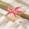 Makroaufnahme: 3-lagiger goldener Ring mit pinkem Seestern-Emaille auf Sand - Rosa