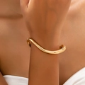 Minimalist gold wavy open bangle with polished finish shown on a woman wrist - Gold Yellow