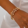 Eleganter goldener mehrlagiger gedrehter Armreif mit polierten Perlen für Damen - Gold