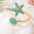 Detalle de estrella de mar dorada y concha de esmalte azul en el brazalete ajustable - Brazalete Estrella de Mar y Concha / Azul