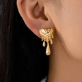 Polished gold liquid heart stud earrings showing melting heart design on model's ear - Gold
