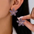 Elegant purple enamel flower stud earrings for women shown worn on a model's ear - Purple