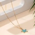 Collana alla moda in oro con ciondolo a forma di stella marina azzurra su sfondo sabbia - Blu Chiaro