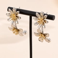 Elegant vintage silver daisy flower earrings with gold center on a display stand - White Gold