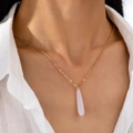 Minimalistische Goldkette mit hellem, durchscheinendem rosa Wassertropfen-Anhänger an Model - Weiß