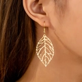 Elegant gold hollow leaf earrings with textured vein design on a female model - Gold
