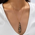 Collar dorado de moda con colgante de gota de leopardo sobre un cuello en V - Estampado de leopardo