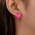 Elegante herzförmige Ohrstecker aus rosa Emaille mit Goldrand, von Frau getragen - Rosarot