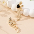Elegant gold earrings featuring black heart charms and fluid metal ribbons on sand - Black