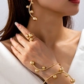 Elegante gouden sieradenset met oorbellen, ring en armband op een vrouwelijk model - Gouden 3-Delige Set (Armring + Oorbellen + Ring)